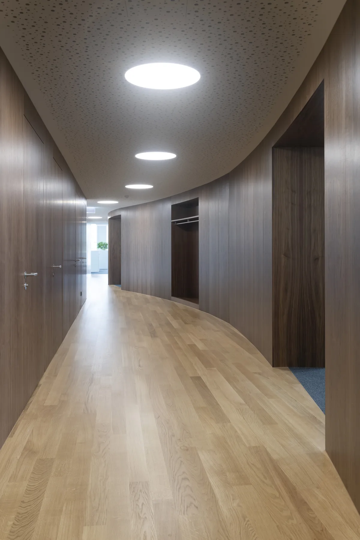 Holzverkleidung im Korridor: Türen und Wandflächen folgen der geschwungenen Raumführung.